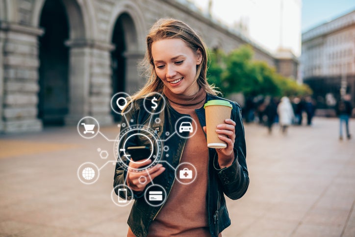 woman holding coffee and looking at phone